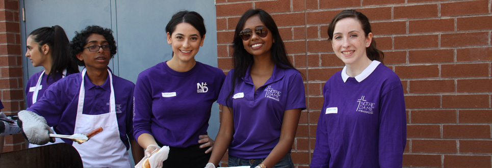 Students wearing purple t-shirts handing out hotdogs