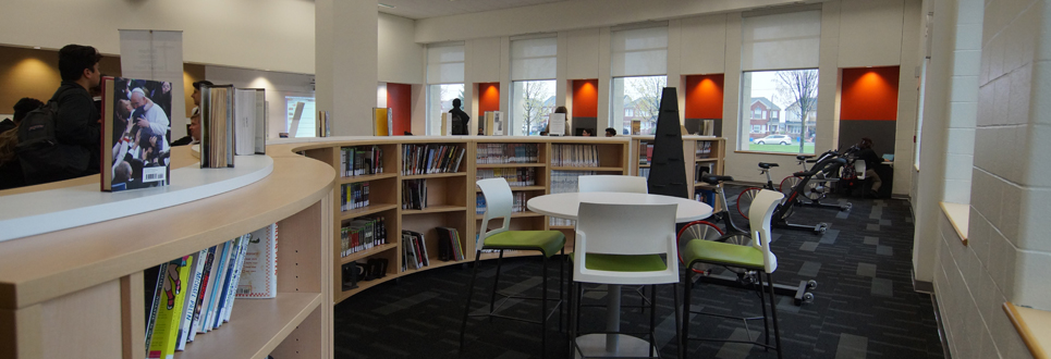 Exercise bikes, table and chairs, books in a Learning Commons