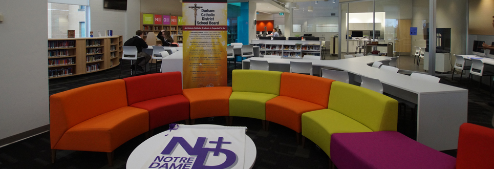 Notre Dame banner on a table, colourful couches, students in the background, books on shelves